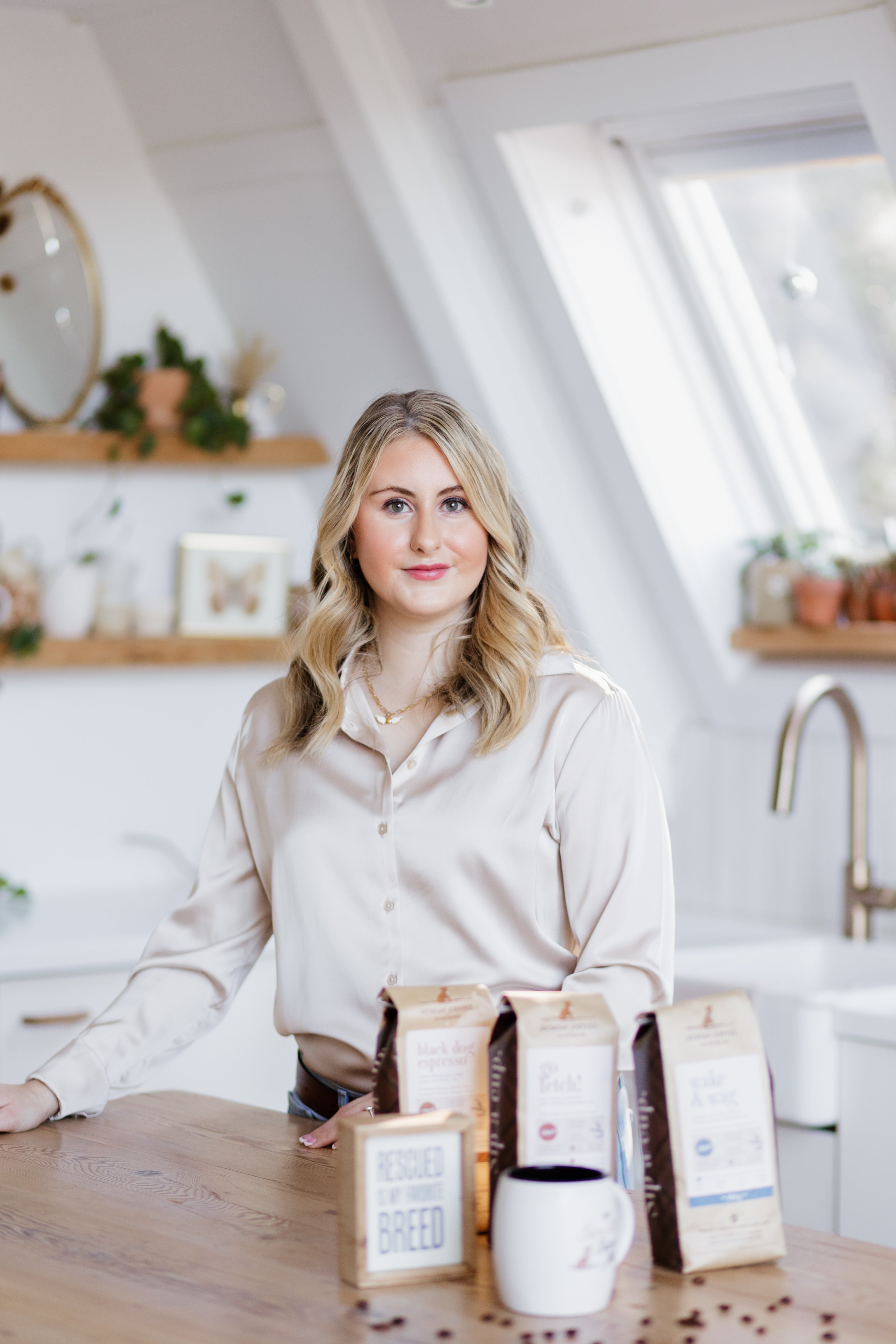 Katie Lunn, owner of Rescue Coffee Co. Standing in a white kitchen with Rescue Coffee Co Beans and a branded mug