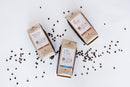 Three packages of pet food on a white background with scattered coffee beans.