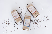Three packages of pet food on a white background with scattered coffee beans.