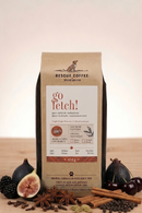 Rescue Coffee bag labeled 'go fetch!' with figs, cinnamon sticks, and cherries on a wooden surface.