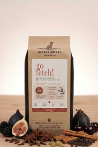 Rescue Coffee bag labeled 'go fetch!' with figs, cinnamon sticks, and cherries on a wooden surface.